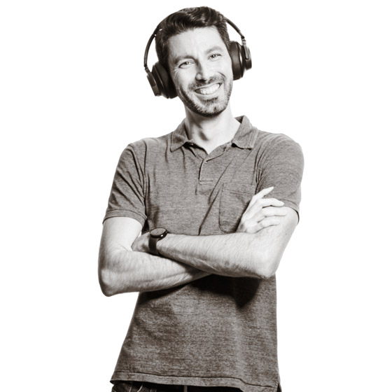 Georg trägt die Bluetooth-Kopfhörer auf den Ohren und grinst breit.