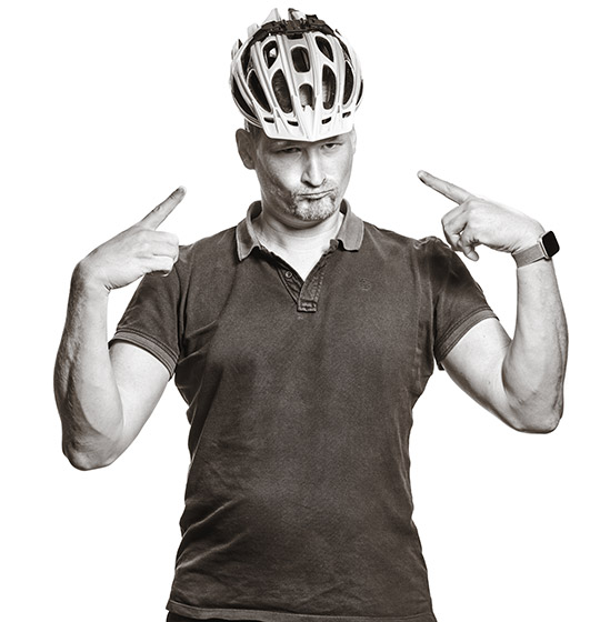 Markus trägt den Fahrradhelm umd zeigt mit beiden Händen darauf wie um zu sagen: "Ich bin der Fahrrad-König!".