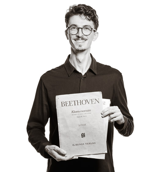 Maximilan hält Notenbücher in den Händen. Auf dem vorderen steht "Beethoven".