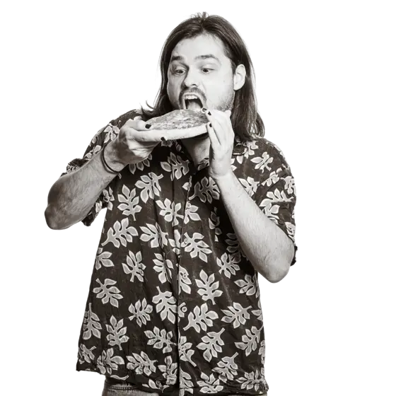 Portrait von Nicolas. Er hält breit lächelnd eine kleine Pizza in die Höhe. 