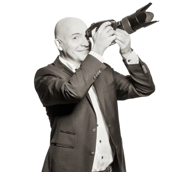 Sven hält eine digitale Fotokamera mit großem Objektiv in der Hand.