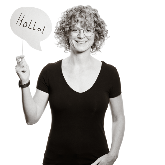 Isabel hält ein Schild in Form einer Sprechbalse hoch, auf dem "Hallo" steht. 